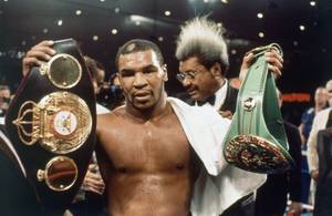 Boxer Mike Tyson holds double championship belts in Las Vegas, Saturday, March 7, 1987 after winning 12-round decision from James Smith to win the WB C/WBA Heavyweight Championship. (AP Photo)