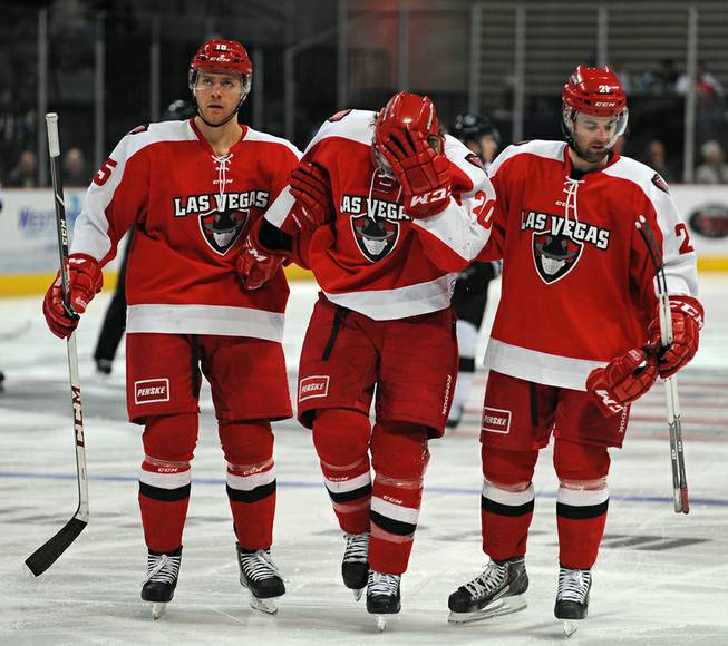 Las Vegas Wranglers foward Robert Smith (center) is helped off the ice by teammates Brendan Rempel, left, and Greg Coburn after suffering a knee injury after a collision with an Eagle player during the third period of play against the Colorado Eagles on Feb. 5, 2014.