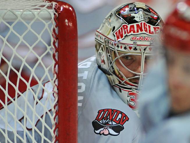 Las Vegas Wranglers goaltender Travis Fullerton keeps his eyes on the puck as it bounces into the corner during the second period of play against the visiting Utah Grizzlies on Friday night at the Orleans Arena on Friday night. The Wrangler players wore special sweaters inspired by UNLV Rebels jerseys that were to be auctioned off during the game to fans with the proceeds benefitting the Dave Rice Foundation.
