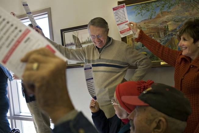 Sen. Harry Reid and his wife, Landra Gould, raise their presidential preference cards to be counted at their home precinct in Searchlight during the Jan. 19 Democratic presidential caucus. Reid hasn't said whom he is backing in his party's nominating race, and his new book offers few clues, praising both Sen. Hillary Clinton and Sen. Barack Obama.