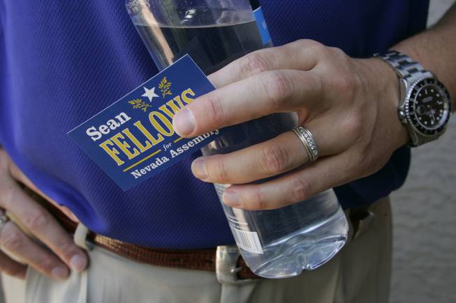 Fellows carries tools of his trade -- his card and a bottle of water -- as he campaigns door to door. Few voters ask about his party affiliation, he says.