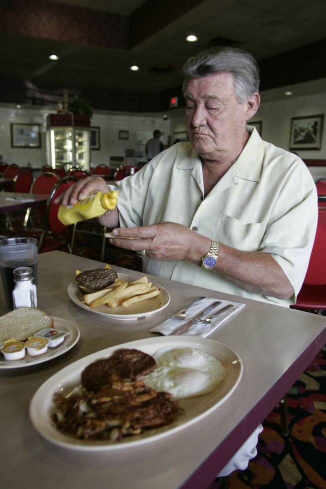 Klondike Sunset owner John Woodrum dresses up a 99-cent hamburger special Thursday.  