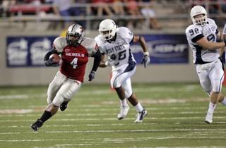 UNLV's Frank Summers runs ahead of Utah State defenders Darby Golden, center, and Casey Davis at Sam Boyd Stadium.
