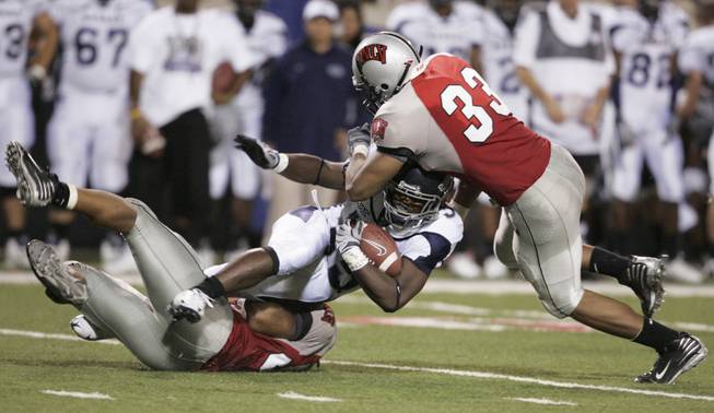 UNLV linebackers Nate Carter, left, and Jason Beauchamp tackle UNR ...