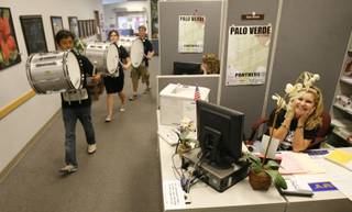 Palo Verde faculty member Tami Stilson covers her ears as members of the marching band roam through the administration office before the school's homecoming rally Friday.