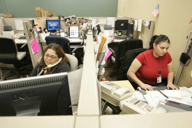 Tricia Benavente, left, helps a voter on the phone while Martha Barraza inputs a voter registration card Thursday.