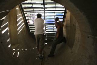 Walking to the end of the ventilation tunnel, Richard Scott, of Los Angeles, and Tui Anderson, right, of Hawaii, peer through the vents of the Hoover Dam to catch a glimpse of the water flowing below.  Attendees of the WaterSmart Innovations Conference toured the Hoover Dam on Friday.