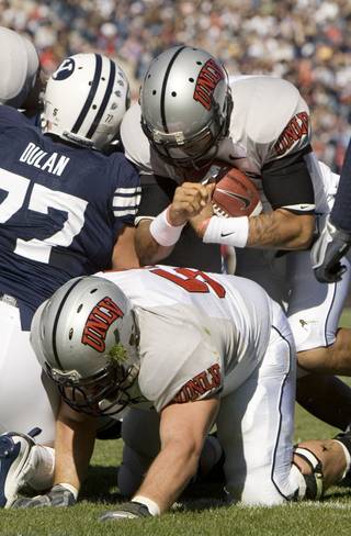 UNLV quarterback Mike Clausen takes the ball past BYU defensive lineman Ian Dulan (77) to score during the second quarter on Saturday. 