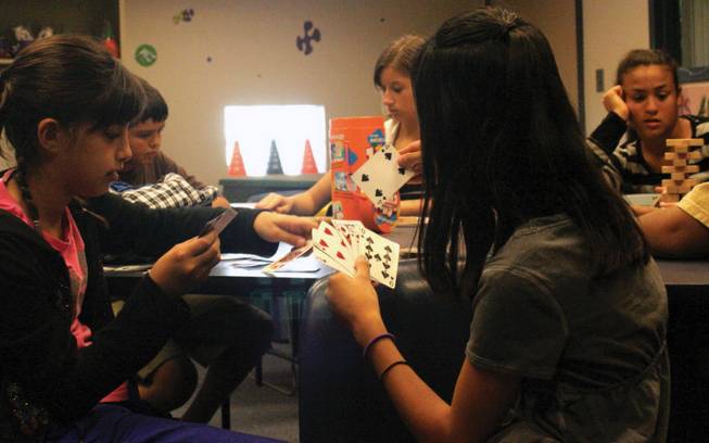 Nina Mares, left, and Alicia Danilaff play cards in the teen lounge at the Whitney Ranch Recreation Center while waiting for walleyball to start.