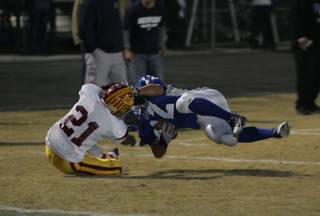 Del Sol's Jordan Molina, left, (21) tackles Basic wide receiver Justin Burdno (12) during the Sunrise Regional semifinals at Basic Friday.