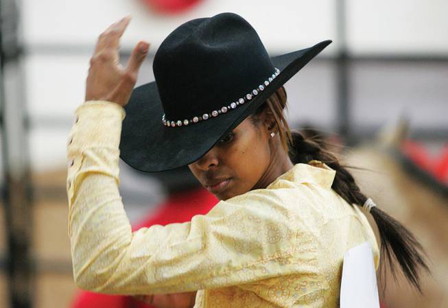 Tiphini Carter adjusts her hat Saturday before competing in barrel racing, an event that tests a rider's ability to turn her steed on a dime repeatedly.