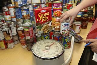 Helen Breeden weighs food donated during the citywide competitive food drive held at Henderson City Hall.  Thirteen departments collected a total of 3,312 pounds of food to be delivered to families in need during the holidays.