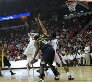 Brice Massamba of UNLV forces a shot up over Max Zhang of California Friday at the Thomas & Mack Center.