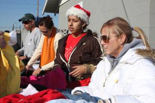 Southeast Career Technical Academy student Karina Moreno, center, and Cimarron-Memorial teacher Judy Jacobs help distribute clothing to families in need during the seventh-annual event for the homeless Saturday at City Mission of Las Vegas.
