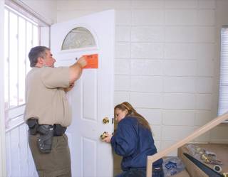 Constable Earl Mitchell, left, places the notice of eviction on the door of a residence while the locks are changed Tuesday.