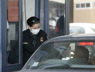 A Customs and Border Protection agent wears a protective mask while interviewing the driver of vehicle entering the United States at the San Ysidro Border Crossing in San Diego on Monday.