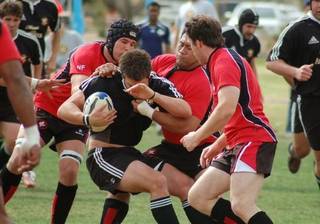 Blackjacks Adie Hall, Ron Tufele and Tom Carter gang-tackle a ball carrier from the Los Angeles Rugby Club, during their March 21 clash at Sunset Park. The 