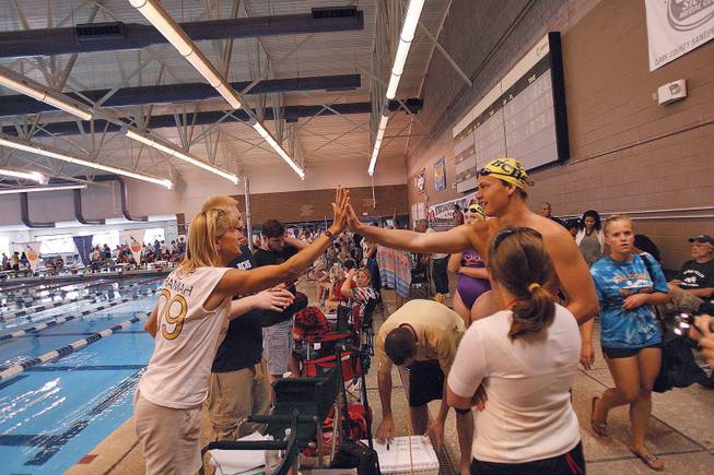Boulder City High swimming coach Sara Carroll, left, congratulates Cameron Walker after sweeping first place in the men's 200 freestyle relay during the Sunset Regional swim meet at the Desert Breeze Aquatics Center.