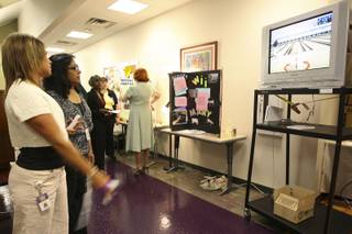 Debi McGuire plays video bowling using her Wii-hab Controller while demonstrating her invention for Kainath Purre, right, Thursday during the annual student Assistive Technology Fair at Touro University.