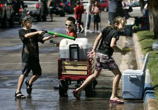 From left, Harley Devorski, Las Vegas, Hunter Brady, Omaha, Neb., and Cezanne Devorski, Las Vegas, chase each other with squirt guns during Damboree festivities in Boulder City on Saturday, July 4. 