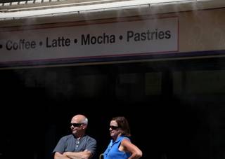 Charles and Elizabeth Booth, visiting from Seattle, stand underneath the misters Wednesday outside the Flamingo Hotel and Casino. The temperature Wednesday topped out at 110 degrees, according to the National Weather Service.