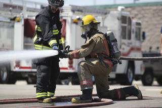 Trainee Daniel Schuster adjusts the flow of water with the guidance of training instructor Chuck Gebhart during a training exercise with the Boulder City Fire Department Aug. 15 at the Henderson Fire Department Training Center.