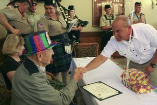 Boulder City Mayor Roger Tobler congratulates World War II veteran Warren Hogue after presenting him with a certificate of appreciation during his 100th birthday party Wednesday at the Nevada State Veterans Home in Boulder City.