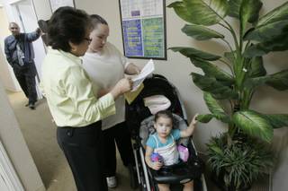 Gloria Roxas hands Nikisha Bangerter her Women, Infants and Children benefits while Danyka Bangerter plays with a plant Wednesday, Sept. 23, 2009.