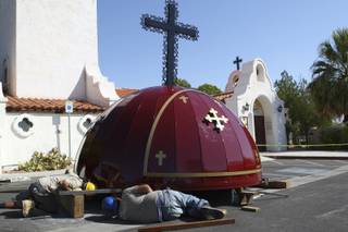 Workers Felipe Arellano and Randy Wright, right, peer underneath the new metal dome as they help secure the sides together before its installation on top of the cathedral tower Monday at St. Jude's Children's Ranch in Boulder City.