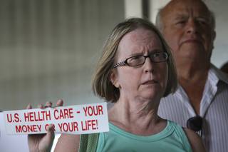 Sandra Hanson holds up a homemade bumper sticker while listening during a rally Tuesday outside the Nevada Republican headquarters. The health care reform rally was organized by Nevada Democrats.