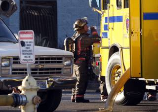 A Clark County firefighter takes a break after putting out a fire in the yard of an electrical supply company on Pepper Lane near Pecos Road Wednesday, Sept. 30, 2009. Burning spools of wire caused black smoke but the fire was contained to the yard.