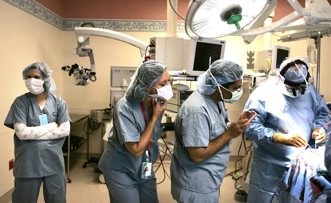 Epilepsy techs Amber Curl, from left, and Karolyn Witcher, with neurologist Dr. Samir Bangalore, watch as neurosurgeon Dr. Stuart Kaplan performs Chris Stones' first brain surgery at Sunrise Hospital & Medical Center on Tuesday, July 14, 2009. Stones will be fitted with electrodes that attach directly to his brain, where his seizures can be more accurately pinpointed.