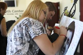 Stevie Scott and Chris Johnson, right, write a note on a poster of Corey Knight during his funeral Saturday at Green Valley Christian Center. Knight, a Del Sol High School senior, died in a car wreck Sept. 25.