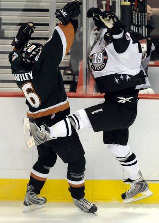Wranglers forward Mick Lawrence, right, takes the worst of a collision with Utah defenseman Victor Bartley during the home opener at the Orleans on Friday night.