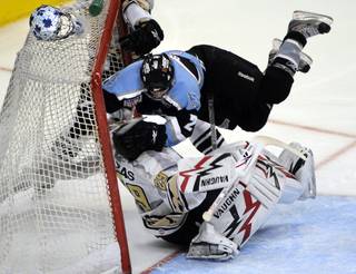 Wranglers goaltender Michael Ouzas is plowed by Aces defenseman B.J. Crum in the third period of play on Saturday night.