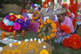 Blanca Gomez arranges paper flowers at a grave site inside the altar of the Clubs of Michoacan, Mexico, presented at at the annual Life in Death: Day of the Dead Festival Sunday night at the Winchester Cultural Center and Park.