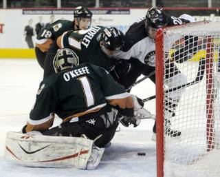 Wranglers right winger Andrew Orpik has his stick held by Grizzly defenseman Evan Stoflet as he attempts to get to a puck behind Utah goaltender Mitch O'Keefe during the second period on Friday night.