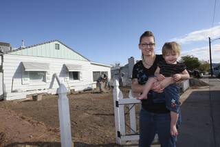 As the recipient of a free lawn-makeover, Tiffany Egbert, 24, stands at the edge of her dirt front yard smiling while holding her one-year-old daughter, Maeve, as contractors renovate her yard Friday as part of the 2nd Annual Operation Green program sponsored by the Nevada State Contractors Board and Nevada Landscape Association.  Egbert's husband, Specialist Kevin Egbert, is currently serving in Afghanistan with the Army National Guard 1221st Calvary. 
 
