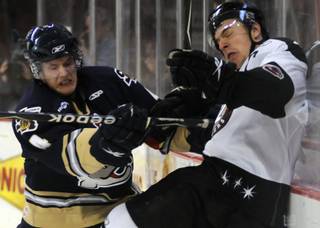 Salmon King defenseman Rob Smith puts a fierce hit on Wranglers veteran Chris Neiszner behind the Victoria net during the second period on Tuesday night.