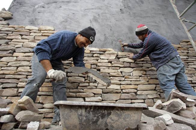 Oscar Rugamas, left, and Elmer Lara of Alvarez Masonry place stones on the exterior of a New American Home on Jan. 8 at 2911 Bella Kathryn Circle. Lack of financing for the project, which was supposed to be completed for next week's International Builders' Show, helped drive builder Domanico Custom Homes out of business.