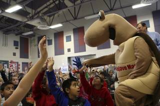 Fourth-grade students raise their hands in excitement as Mojave Max calls on them to answer quiz questions during the Mojave Max Emergence Contest assembly Tuesday morning at Kitty Ward Elementary School.