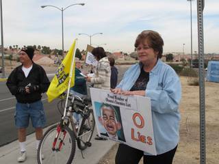 Protesters hold up signs and chant on a sidewalk at Green Valley High School Friday during the president's town hall meeting.