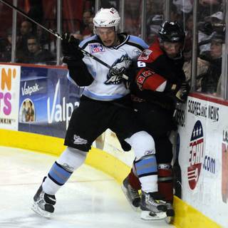 Aces defenseman Ryan Turek (left) checks Josh Prudden into the boards behind the Alaska net late in the third period on Saturday night.