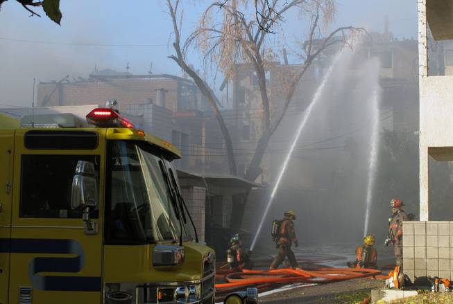 Firefighters spray water on an apartment building that caught fire Dec. 23, 2009, near the Boulevard Mall. Clark County and Las Vegas officials are announcing today that each will mothball one of their specialized fire teams and allow the other government to provide that service across both jurisdictions.