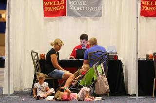 Eva and Douglas Skifton, along with their three toddlers, meet with Wells Fargo representative Richard Tomasso organizing documents in preparation to meet with a home retention specialist during the Wells Fargo free Homeownership Preservation Workshop Friday, July 9, at the Hilton Convention Center.