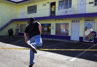A law enforcement officer steps over police tape during an investigation at a medical marijuana clinic at East Sahara Wednesday, Sept. 8, 2010. Authorities say police and federal agents are serving search warrants at several locations in an investigation of medical marijuana clinics in and around Las Vegas.