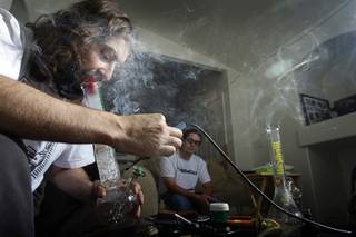 James Parsons, licensed medical marijuana patient and president of Medical Cannabis Consultants of Nevada, smokes marijuana at his home as Licensed medical marijuana patient Justin Martin looks on Tuesday, October 26, 2010.  Parsons was one of several Las Vegans who was targeted by the Drug Enforcement Administration and Metro Police in a crackdown Sept. 8 on individuals who grow marijuana for medicinal purposes. Parsons is legally registered with the state to harvest marijuana for medicinal purposes but his business and Summerlin home were raided. To this day he has still not been charged.