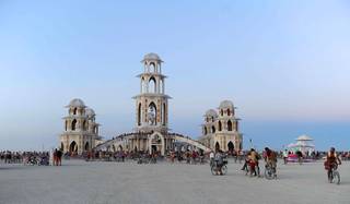 In this Aug. 30, 2011, photo, people gather at the temple during the Burning Man festival in northern Nevada. The temple,  built for the festival in downtown Reno, was hauled in pieces earlier this month on 20 flatbed trucks to the Black Rock desert, where about 140 volunteers from around the world helped with construction. During the festival, which began Monday, people can leave messages and mementos at the temple to help them move on after the loss of a close family member or friend. The temple will be burned on the morning of Sept. 4, which is the day after 
