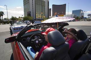 Art Greenberg and Febe Soriano wait for the start of the Barrett-Jackson Road Rally car parade Wednesday, Sept. 21, 2011. Greenberg had the convertible top down on his 2011 Mustang GT, but Soriano protected herself with a hat and parisol. 