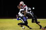 Liberty running back Niko Kapeli leaps over Basic safety Willie Evans (9) while being grabbed by defensive end Garrett Spitzmesser during their game Thursday, October 6, 2011 at Basic. Liberty won 56-21.